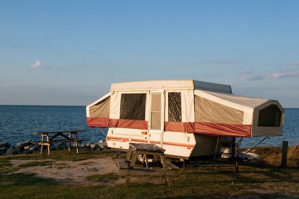 A pop up trailer set up at a beach campsite